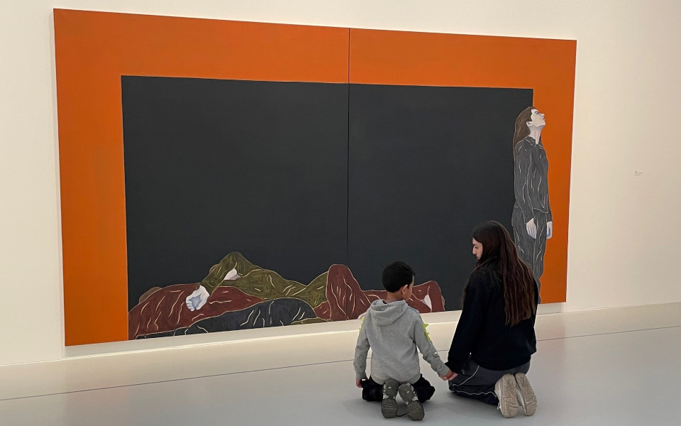 Un jeune garçon et une jeune fille sont agenouillés devant un tableau de Djamel Tatah et se tiennent la main