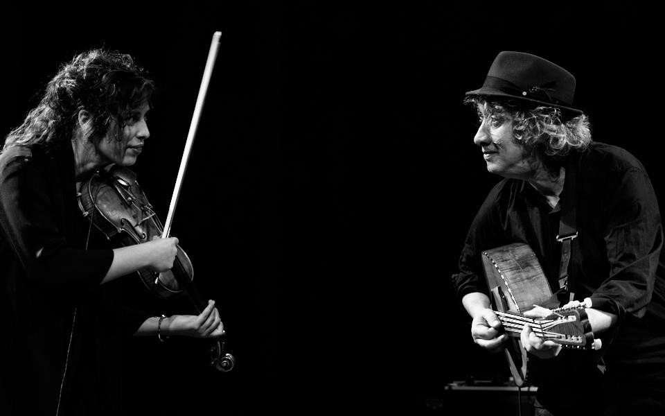 Photo en noir et blanc représentant deux musiciens se faisant face. À gauche, une violoniste ; à droite, un guitariste.