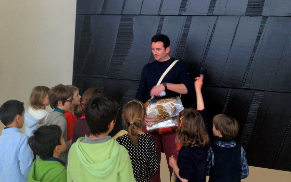 Devant un tableau de Pierre Soulages, un médiateur pose des questions à un groupe d'enfants