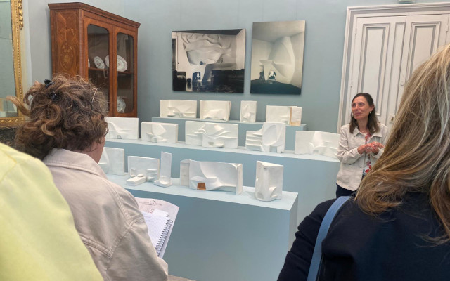 Dans une salle aux murs bleu-gris, une conservatrice de musée présente des œuvres de Velentine Schlegel : 13 maquettes de cheminées blanches en plâtre, sur un podium à trois étages.